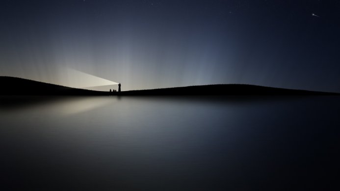 A lighthouse shines brightly at night, reflected in the still water