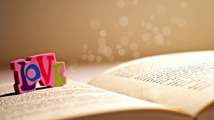 Colorful love block letters on an open book with warm lighting and bokeh effect