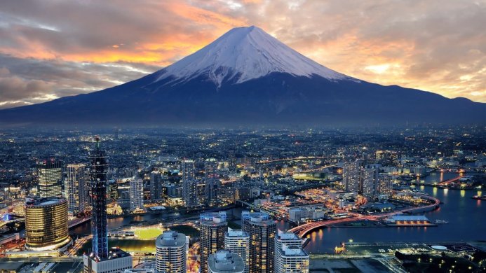Mount Fuji overlooking a sprawling cityscape at sunset