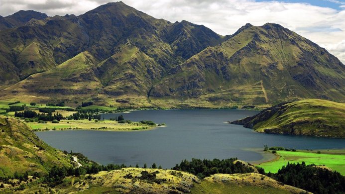 Panoramic view of a lake surrounded by mountains on a cloudy day