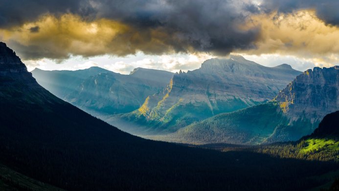 A panoramic view of mountains with sunlight filtering through the clouds