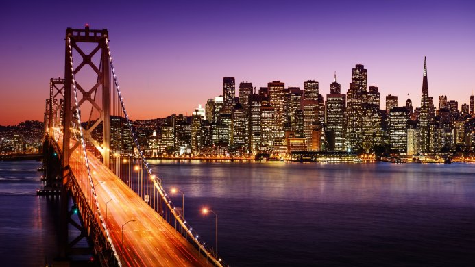 San Francisco Bay Bridge at night with city skyline illuminated in the background