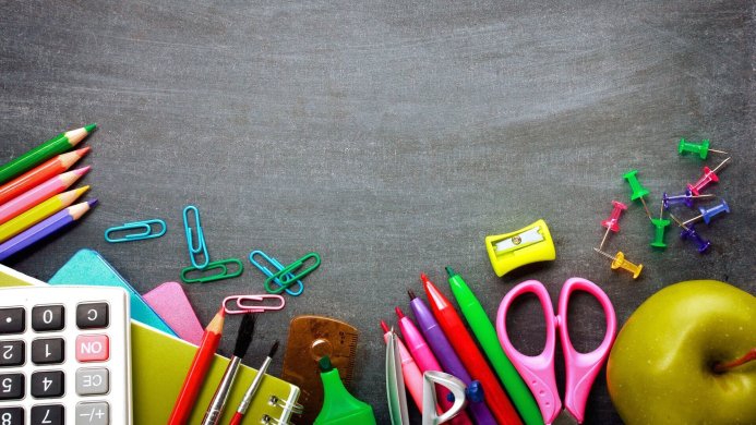 School supplies including pencils, calculator, and apple on a dark gray background