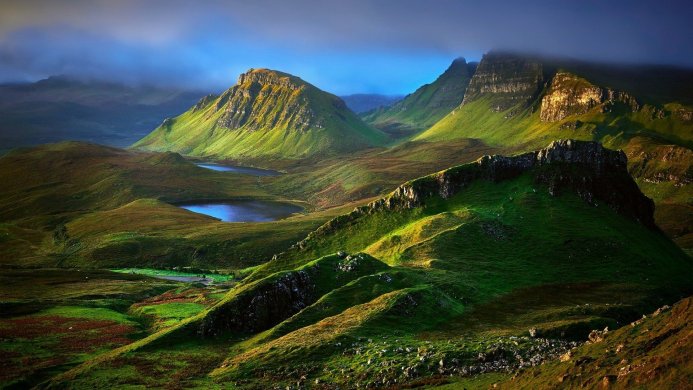 A landscape with mountains, lakes, and green hillsides, shrouded in mist