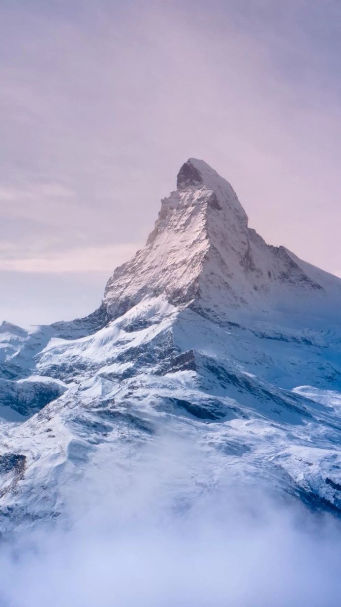 Snow-covered mountain peak against a light sky, a landscape of the Alps in winter