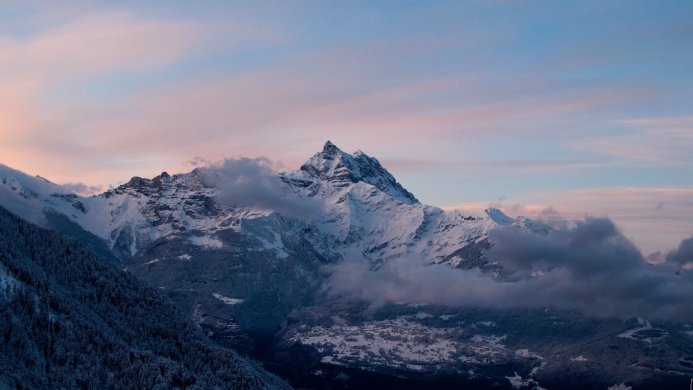 Snowy mountains with clouds at sunset
