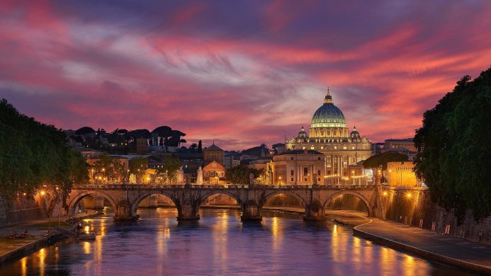 St. Peter's Basilica and a bridge over the Tiber River at dusk in Vatican City