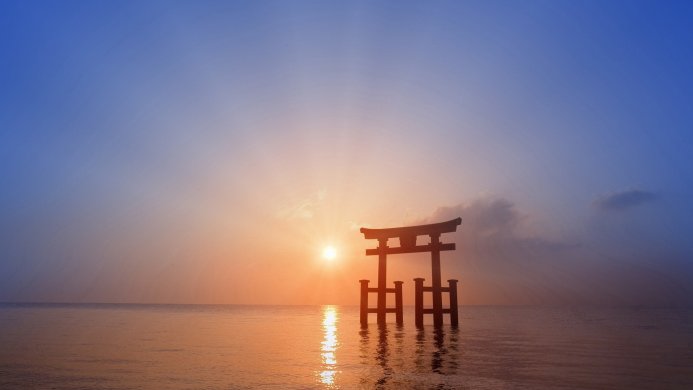 Torii gate in the ocean at sunset, orange sun