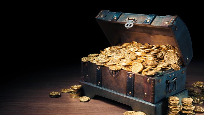 Open treasure chest filled with gold coins on a wooden surface against a dark background