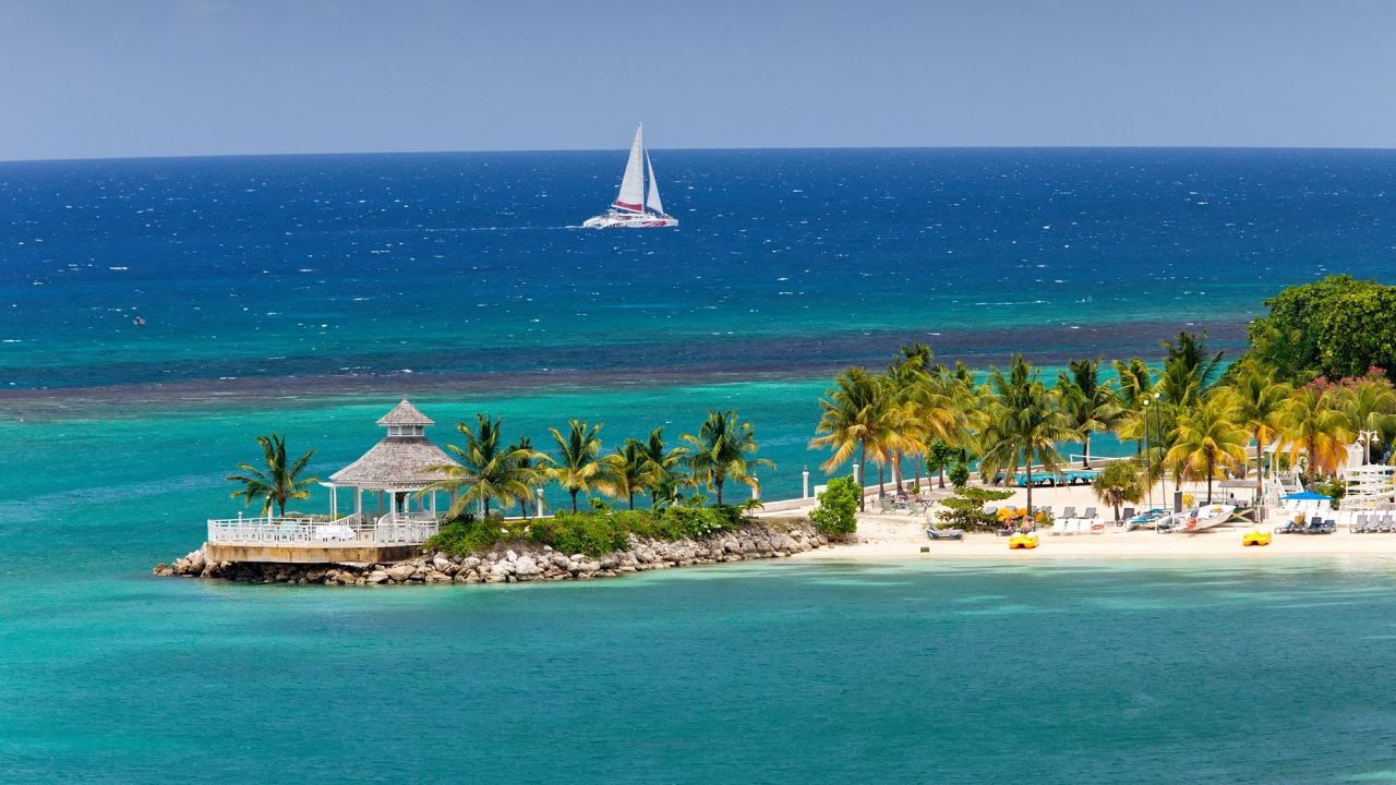 Tropical beach with gazebo and sailing boat