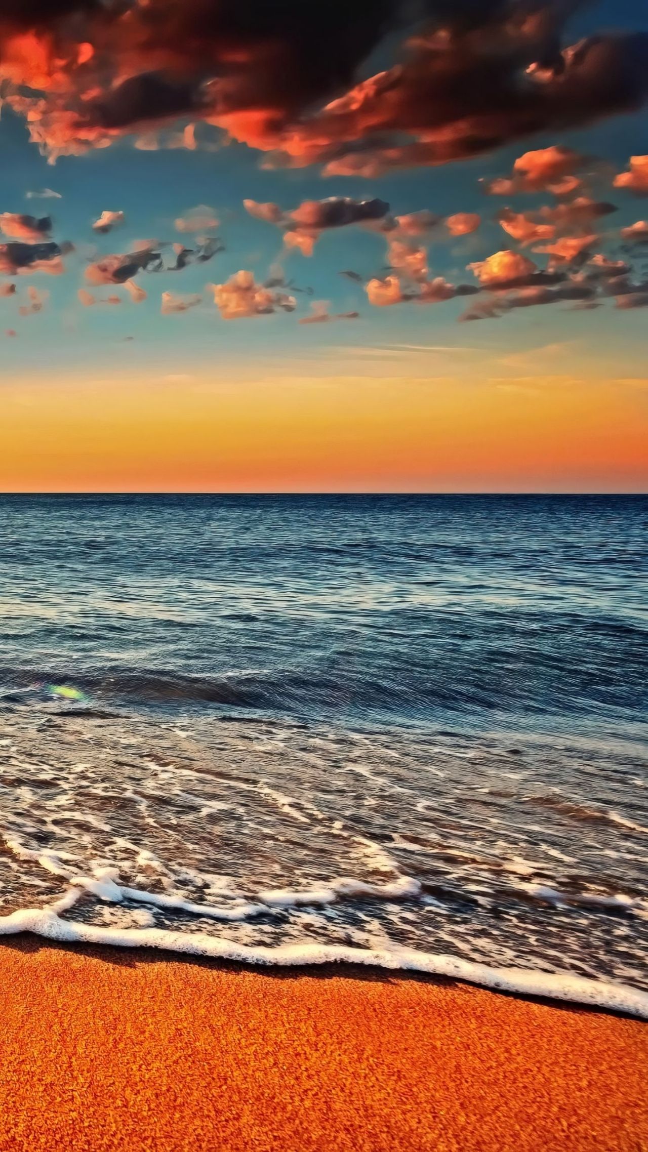 Sunset over ocean waves on sandy beach