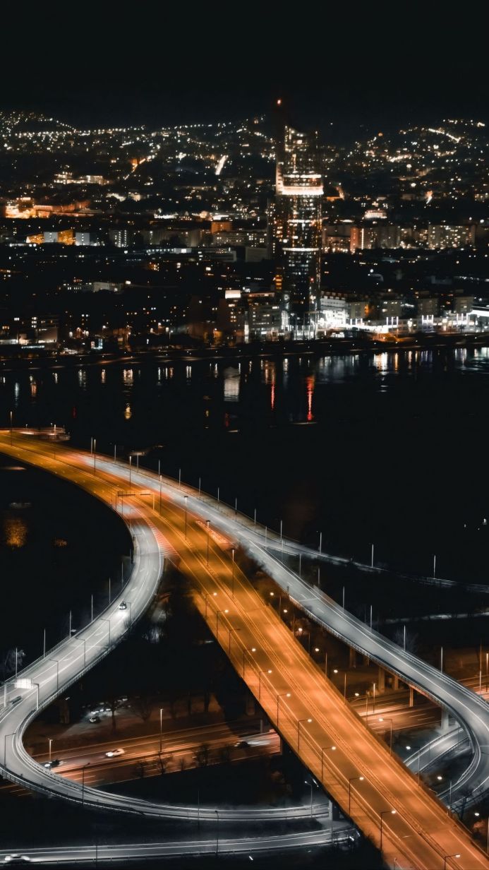 A nighttime view of a city and an illuminated bridge with light trails from moving vehicles