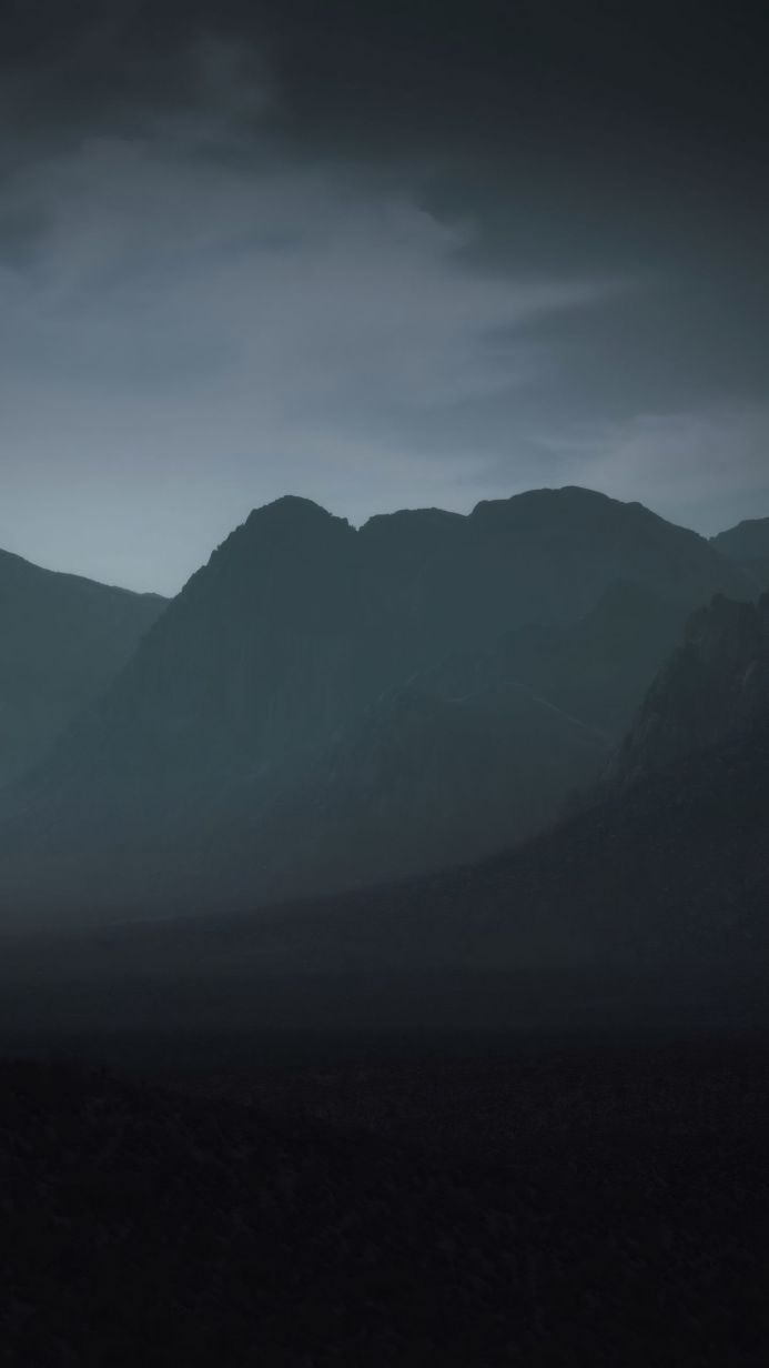A dark mountain range under a cloudy sky