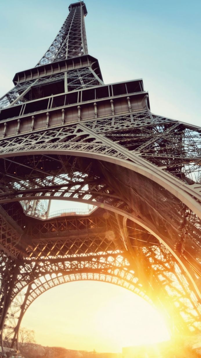 Eiffel Tower seen from below, bathed in the warm glow of the sun
