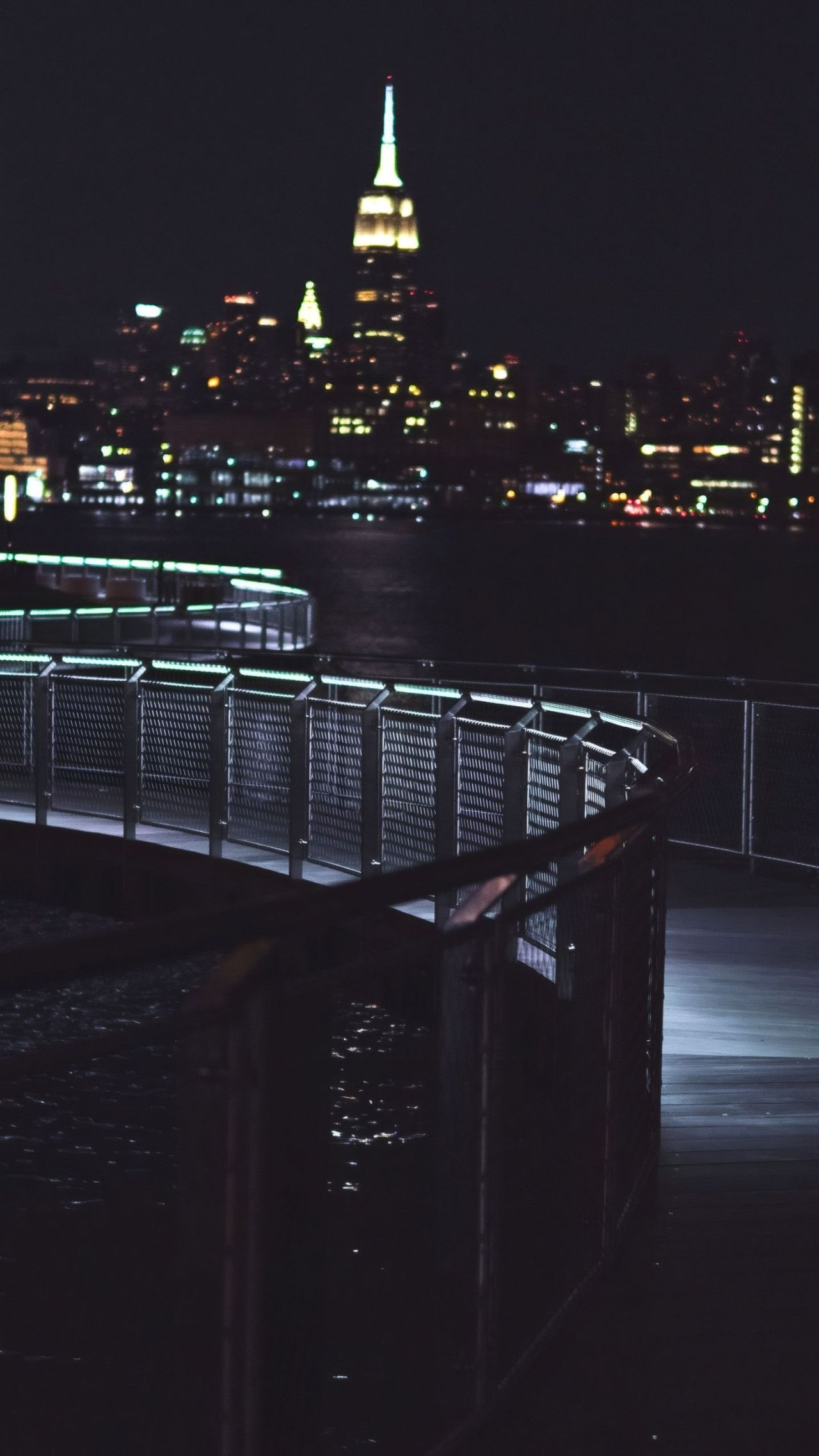 Night view of a waterfront walkway with city lights