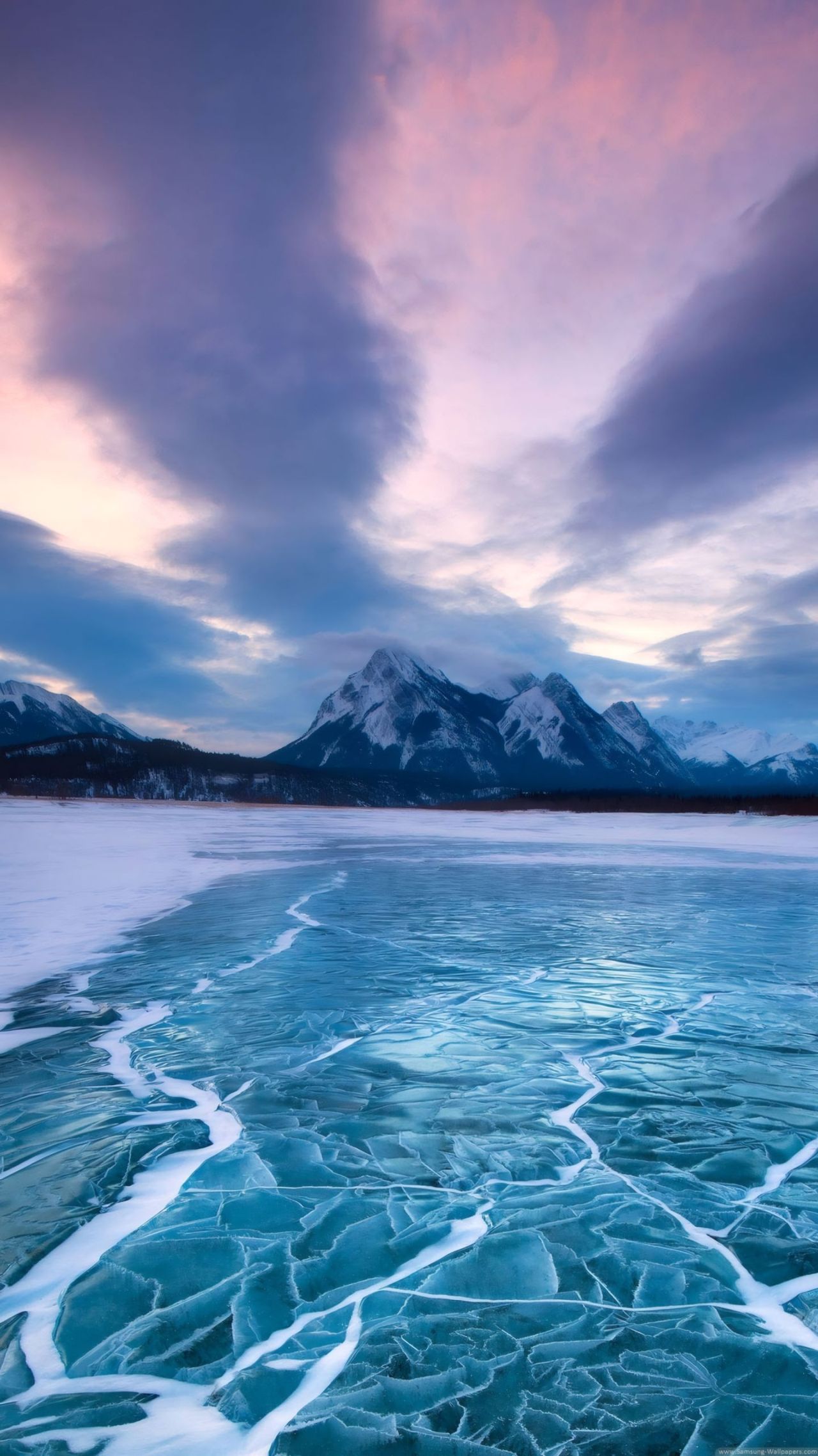 Cracked ice on frozen lake mountains at twilight