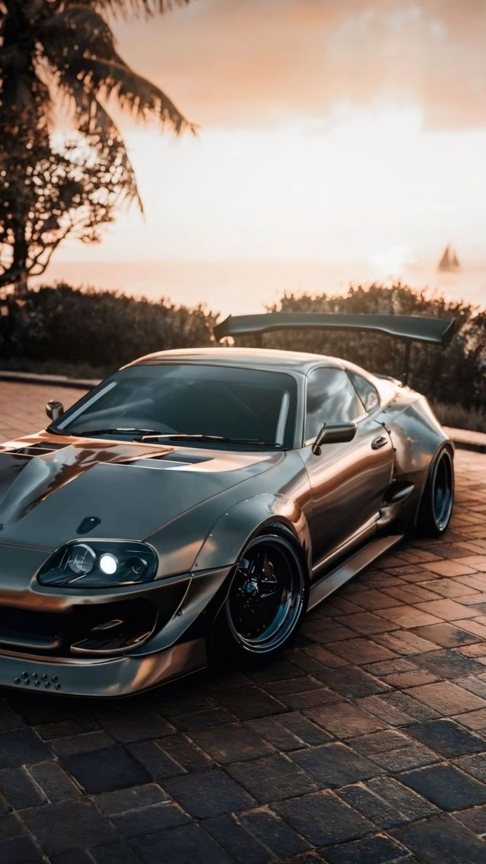 Gray Toyota Supra sports car parked near the ocean during sunset