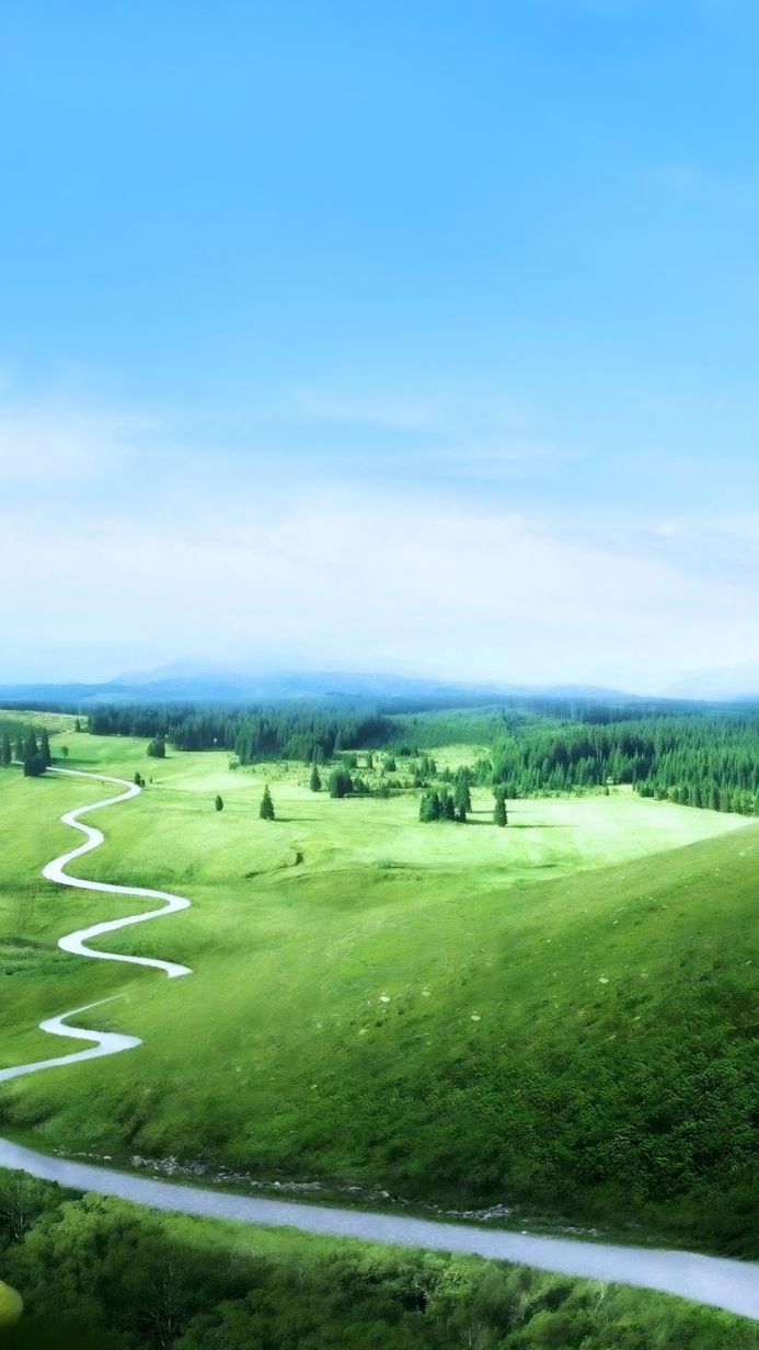 Green landscape with a winding river and forest against a blue sky