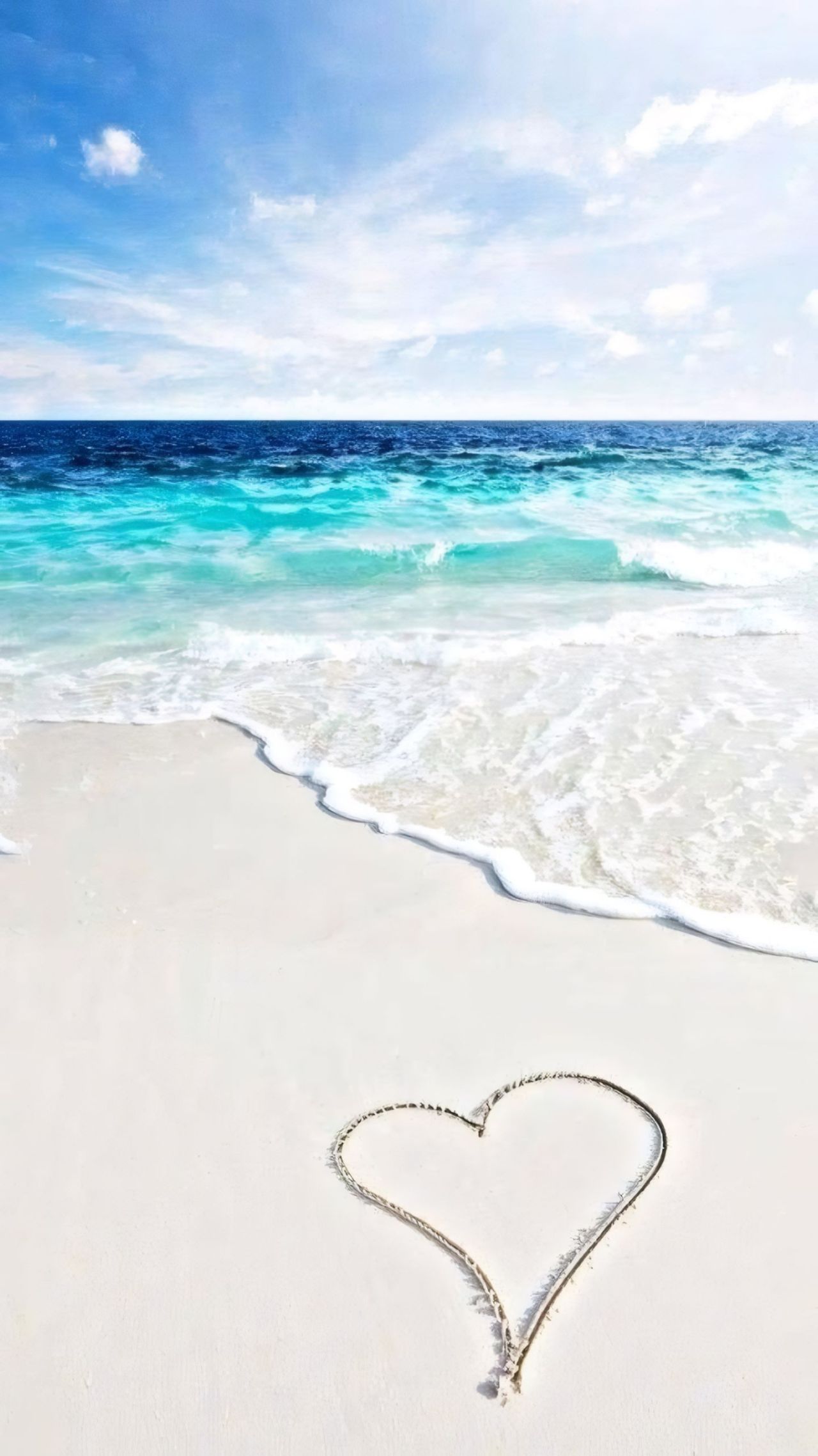 Heart drawn in the sand on a beach with ocean and sky