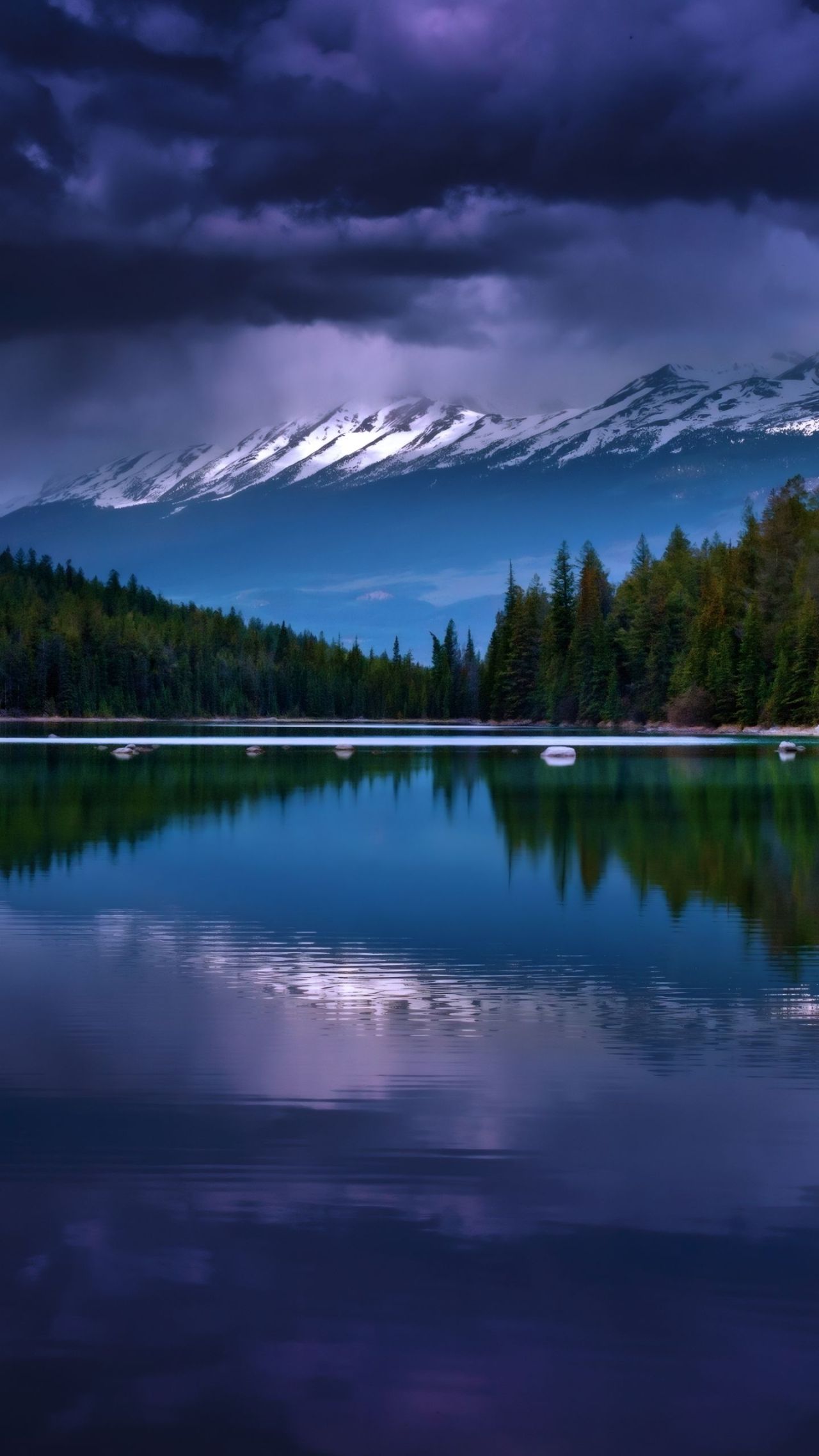 Reflection of mountains forest and dramatic sky in lake