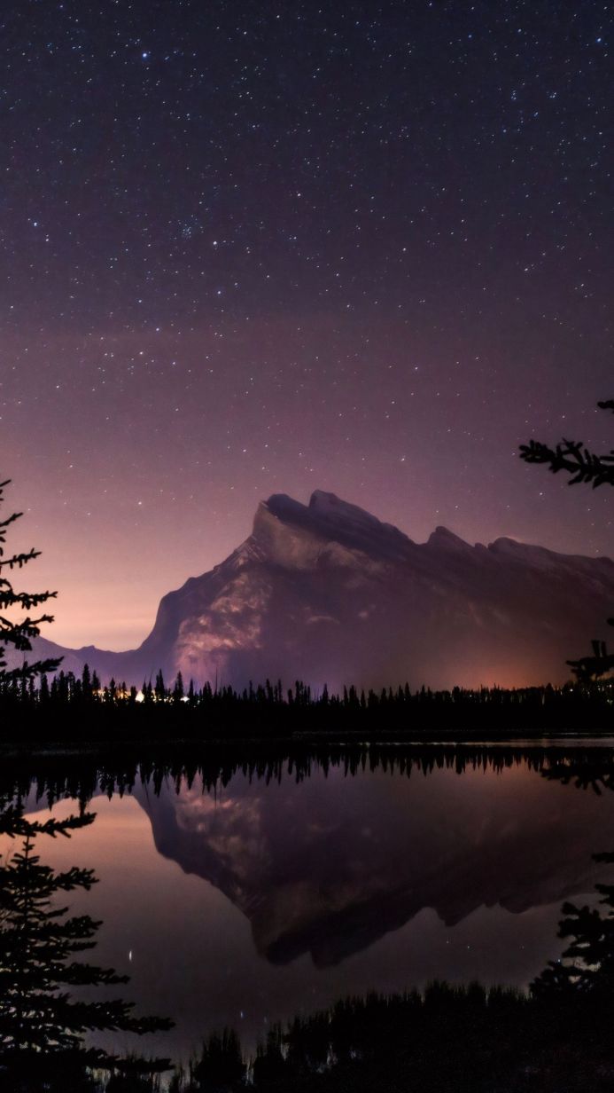 Mountain and lake reflection at night with stars in the sky