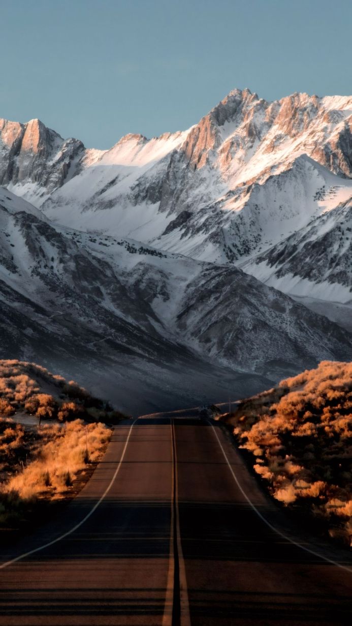 Road leading to snow-covered mountains under a clear blue sky