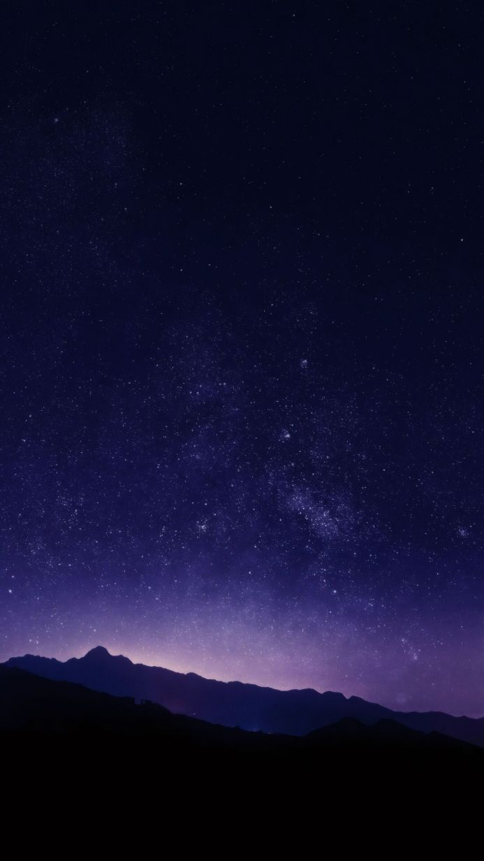 Mountains silhouetted against a vibrant, star-filled night sky