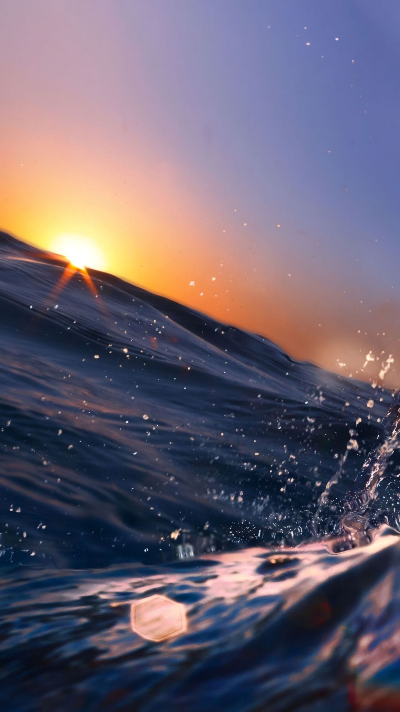 Close up view of a wave at sunset with water spray
