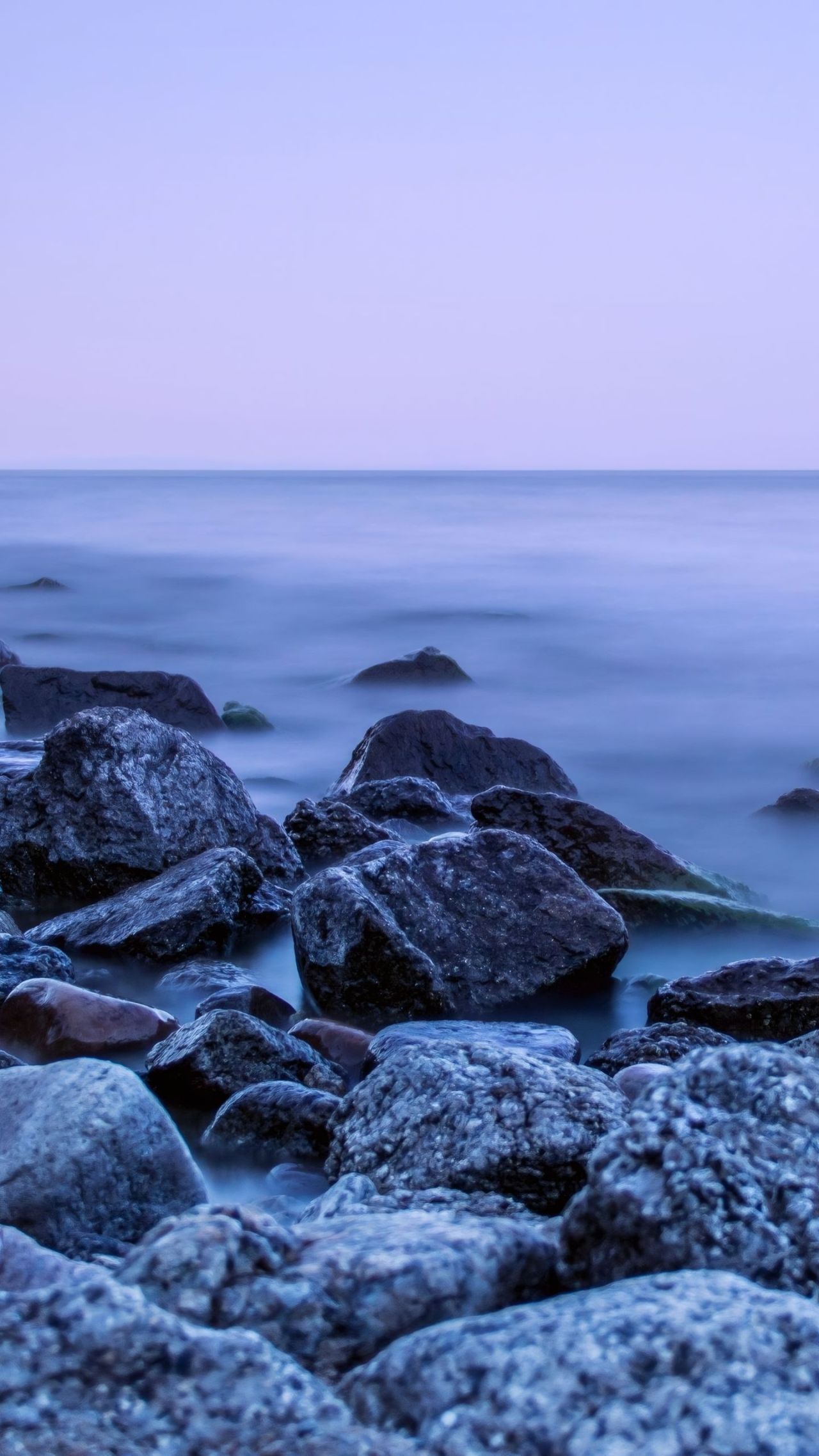 Rocks and blurred water on a beach at twilight