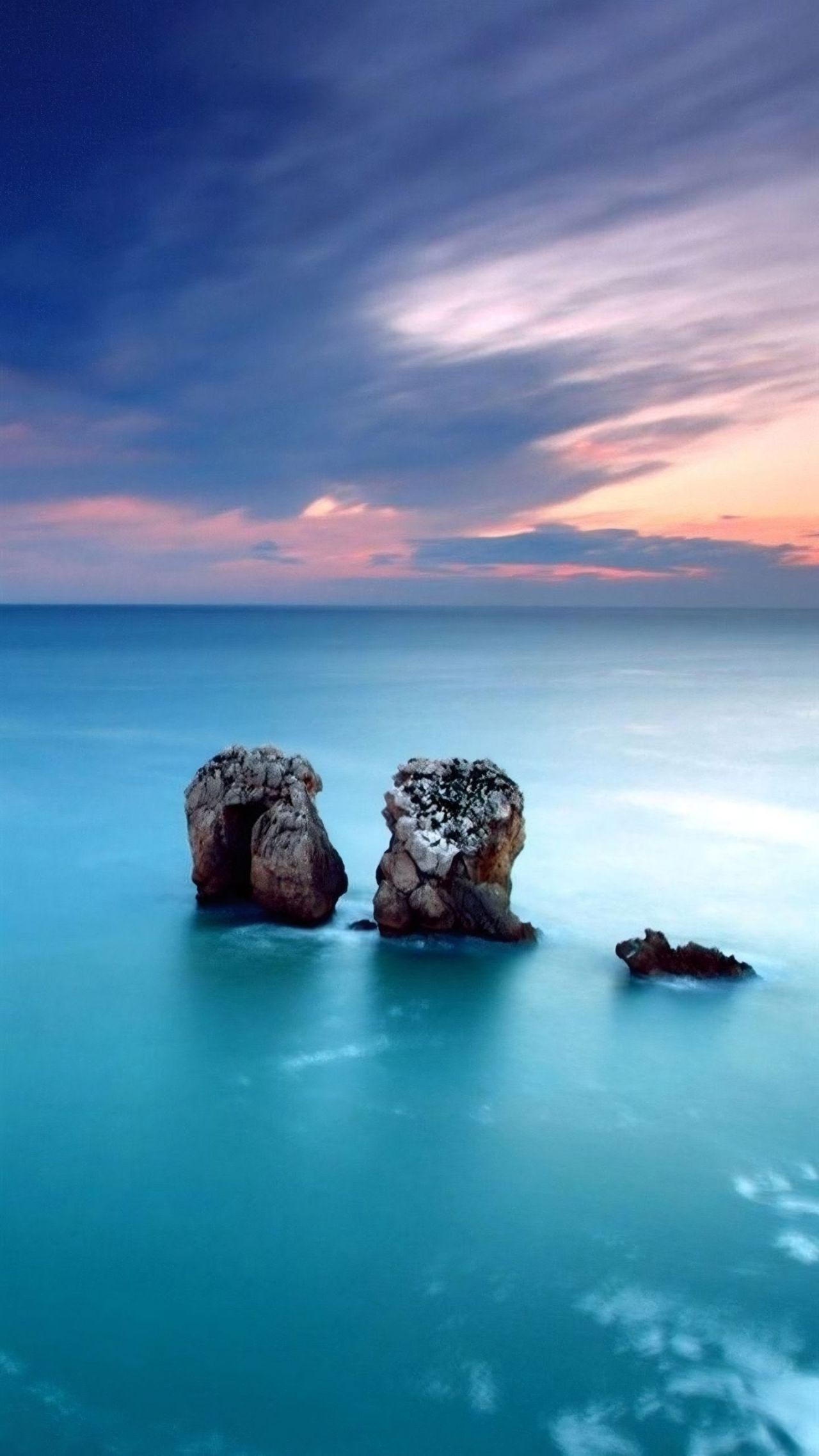 Rocks in blue ocean at sunset