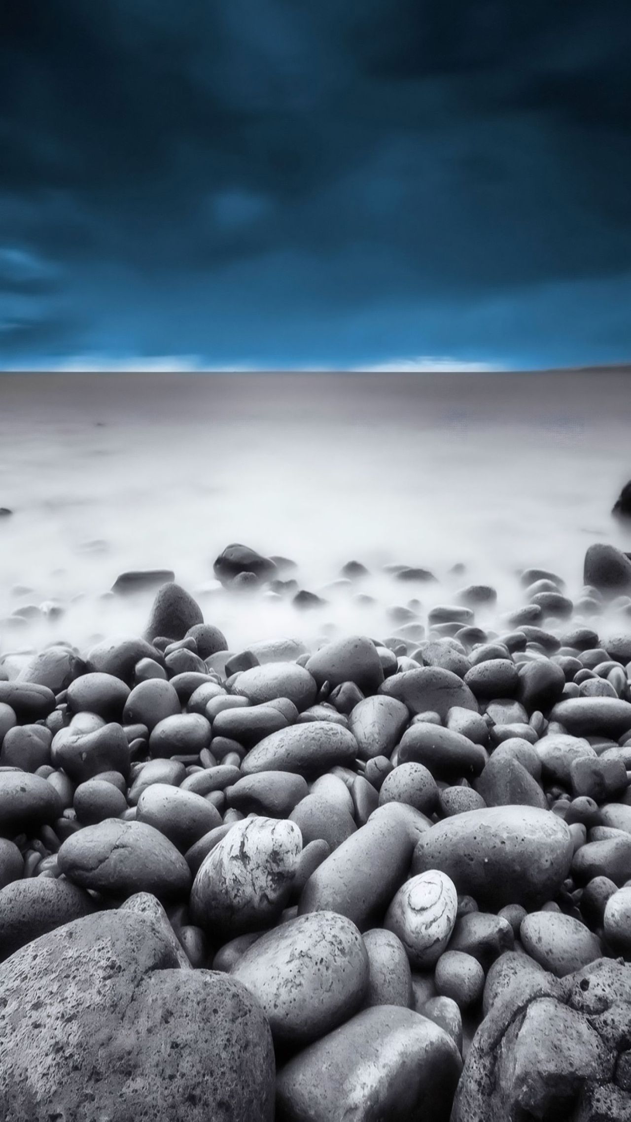 Smooth grey rocks beach long exposure stormy sky