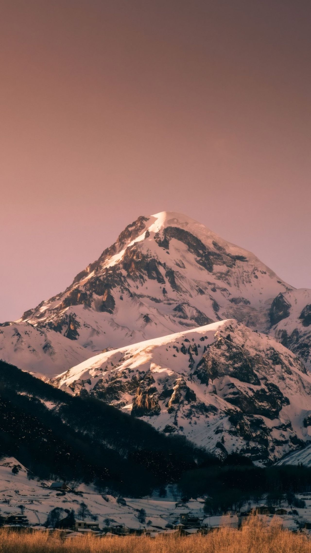 Snow covered mountain peak at sunrise or sunset