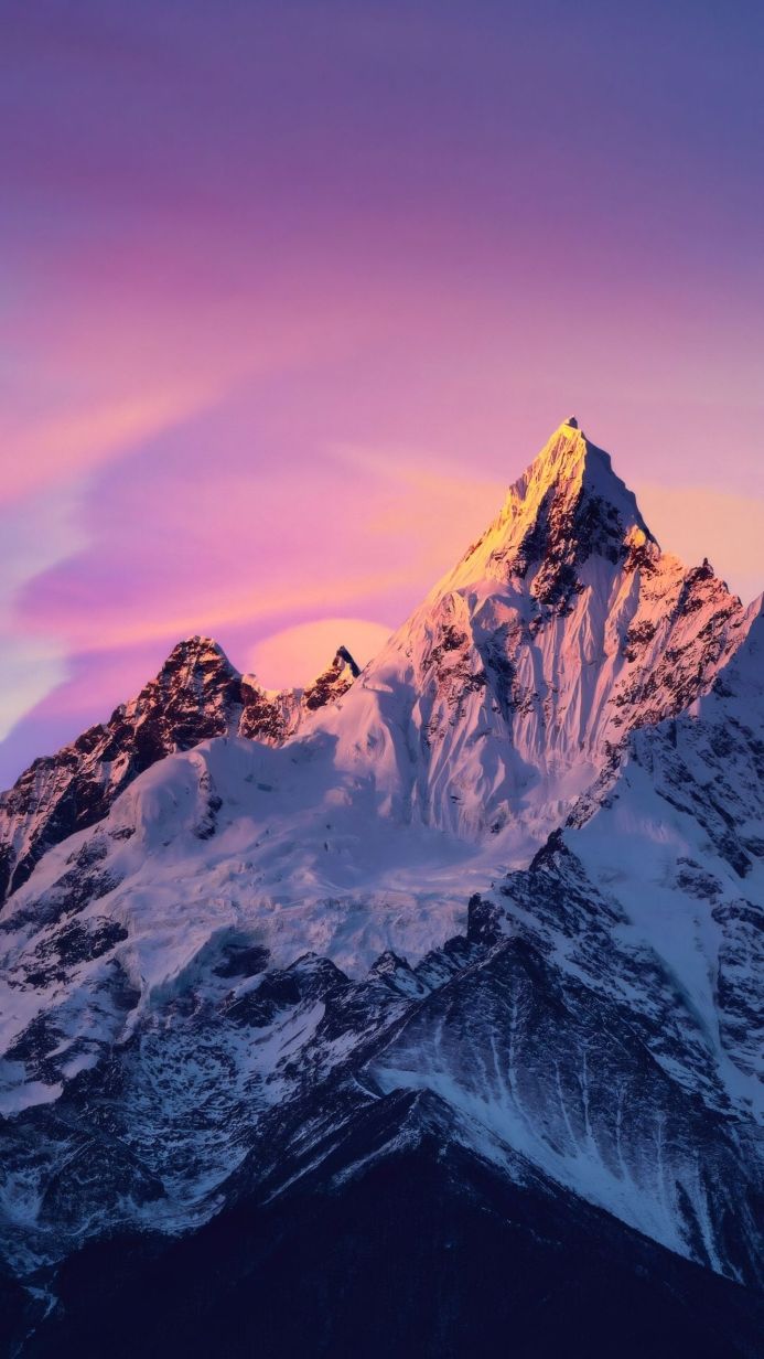 Snowy mountain peak at sunrise with pink and purple sky