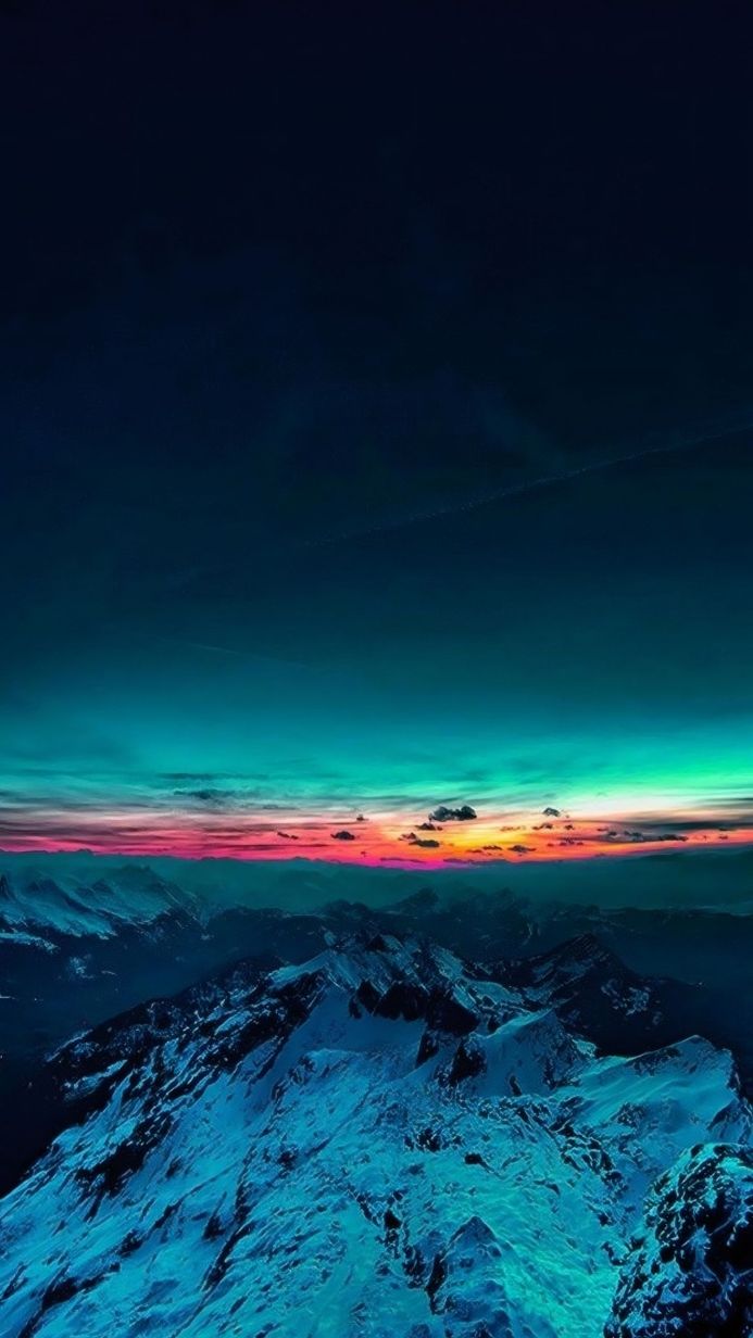 Snow-capped mountains under a colorful sunset sky, with shades of blue, teal, pink, and orange