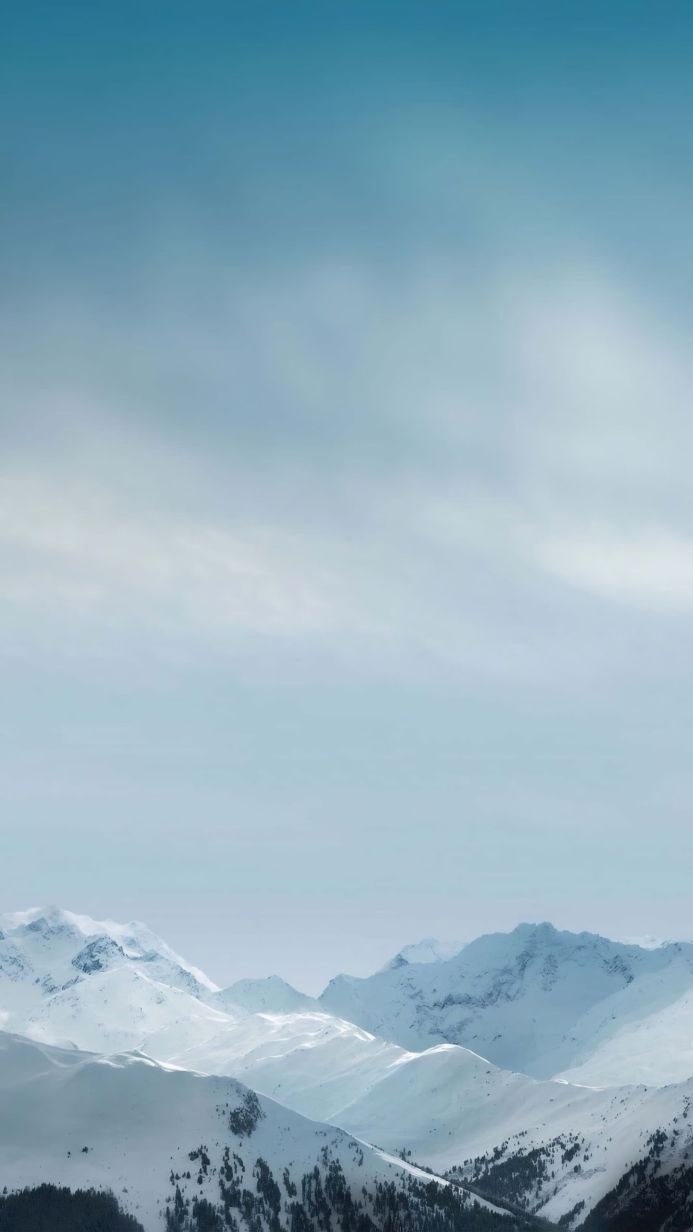 Snowy mountain range under a pale blue sky