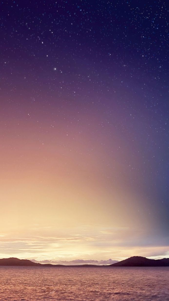 A landscape with a starry night sky above water and land in shades of purple, blue, orange, and pink