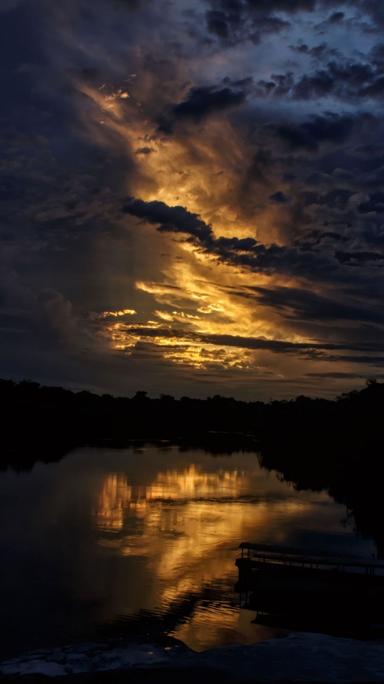 Dramatic clouds reflect golden light on a river at twilight