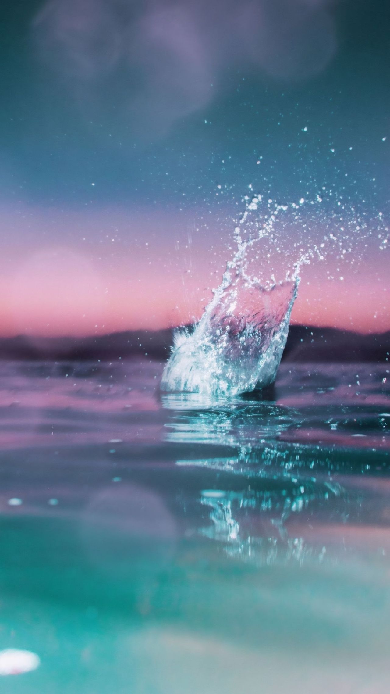 Water splash against sunset colored sky