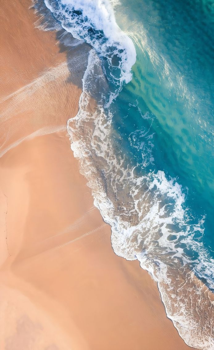 Aerial view of a beach with turquoise waves lapping the shore