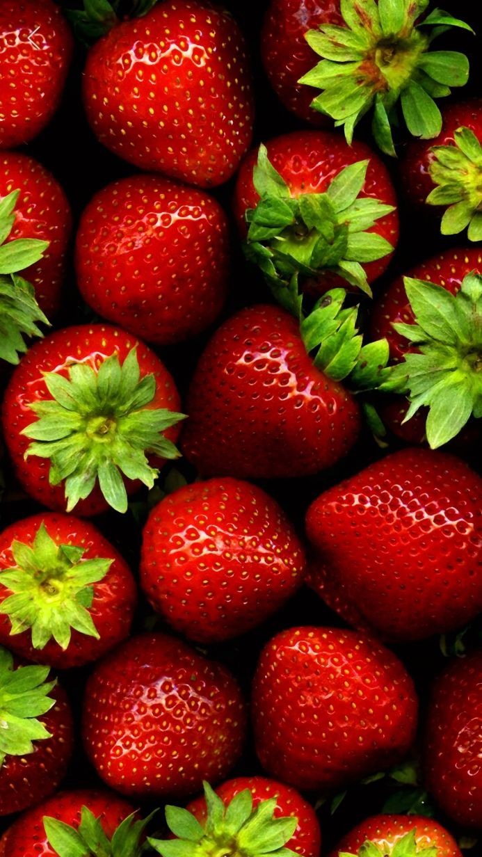 Close-up of fresh, ripe strawberries with green leaves on a dark background