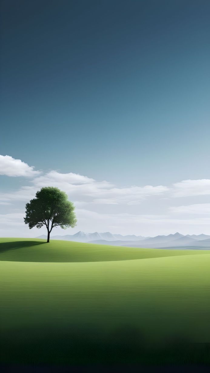 A lone tree in a green field under a blue sky with soft clouds and distant mountains