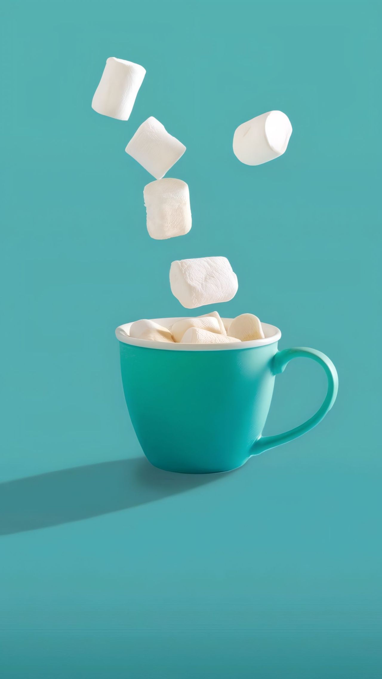 Marshmallows falling into a blue cup