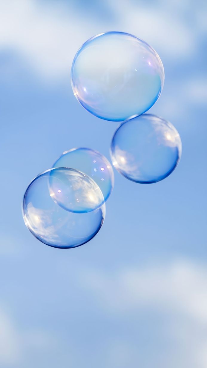 Several transparent soap bubbles floating in a blue sky